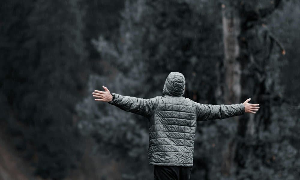 Person spreading arms on a mountain cliff